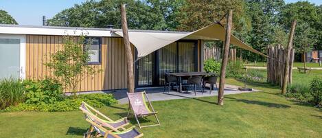 Une terrasse extérieure moderne, dotée d’une table et de chaises, entourée d’une clôture en bois et de verdure.