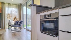 A modern kitchen with a built-in oven and a dining area with a chair and a vase of dried plants. - Lovely home in Voorthuizen with WiFi (Voorthuizen)