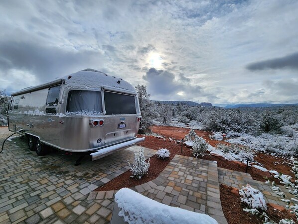 A stationary RV parked on a paved driveway with a snow-covered landscape and distant mountains in the background. - Sedona Epic Dream! 5BR Pool/Slide/Spa/Sauna! (Sedona)