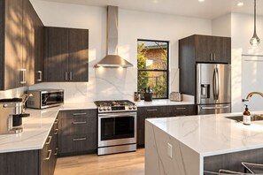 A modern kitchen with dark wood cabinets, stainless steel appliances, and a large island with a sink. - Sedona Epic Dream 5BR 2xPool w/Slide Rooftop Hottub / Sauna / Firepit (Sedona)