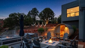 An outdoor patio with Adirondack chairs, a fire pit, and a hot tub.