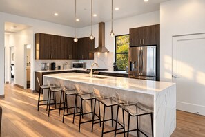 A modern kitchen with a large island, stainless steel appliances, and bar stools. - Sedona Epic Dream 5BR 2xPool w/Slide Rooftop Hottub / Sauna / Firepit (Sedona)