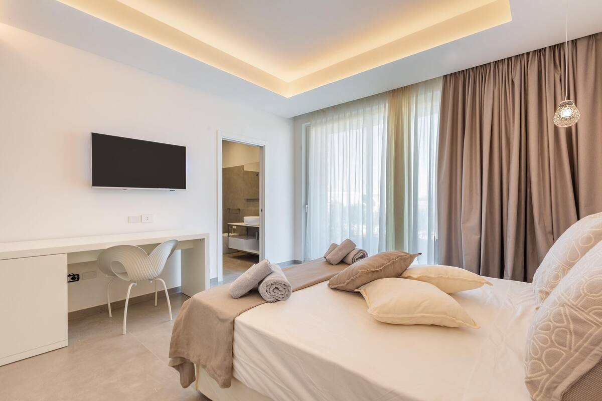 Ein modernes Hotelzimmer mit Bett, Schreibtisch und Fernseher.