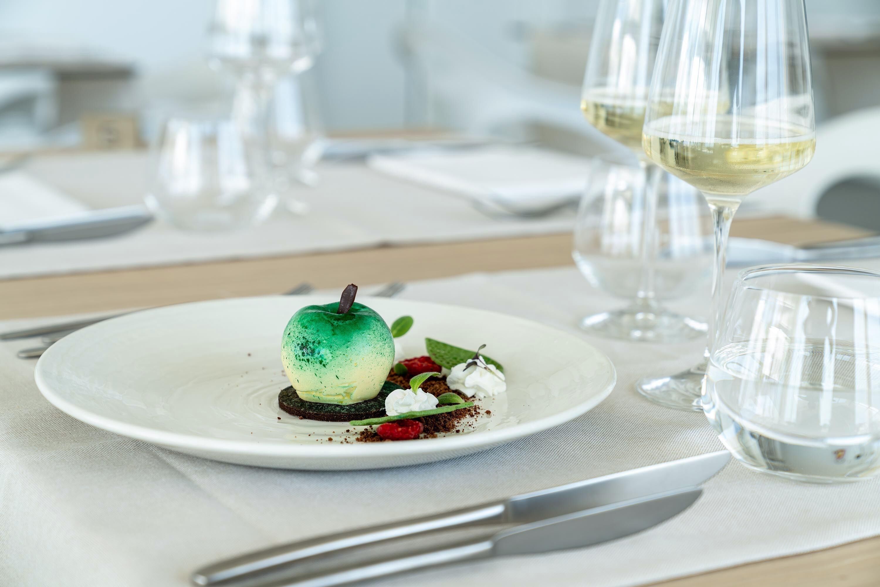 A dessert on a plate with a wine glass and a water glass in the background.