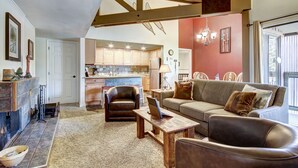 A spacious living room with a fireplace, a sofa, a coffee table, and a dining area with a chandelier. - 2BR/2BA Condo on Shuttle Route - Wild Irishman 1015 - Pool & more! (Keystone)