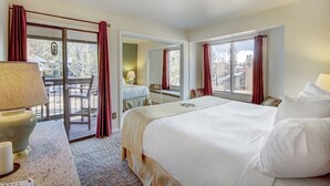 A hotel room with a large bed, a desk with a lamp, and a view of a balcony with outdoor seating. - 2BR/2BA Condo on Shuttle Route - Wild Irishman 1015 - Pool & more! (Keystone)
