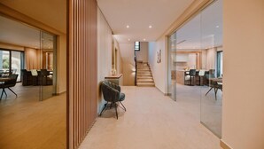 Een moderne hotellobby met een trap, glazen scheidingswanden en zithoeken.