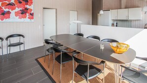 Een moderne eetruimte met een lange tafel, zwarte stoelen en een gele kom op de tafel.