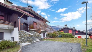 Un edificio moderno con una escalera de piedra, una puerta roja y montañas al fondo.