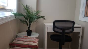 A small room with a desk, chair, and a plant. There is a sign prohibiting smoking and vaping.