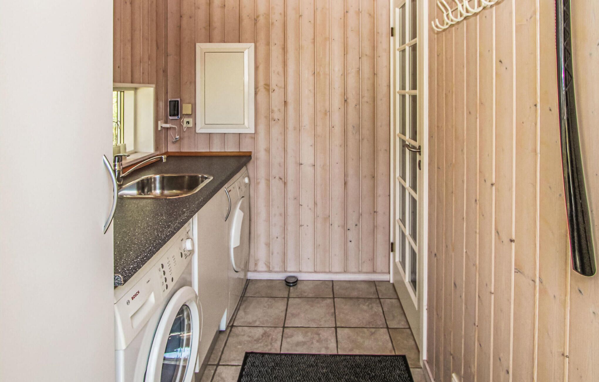 A compact kitchen with a sink, Bosch washing machine, and a door with a mirror.