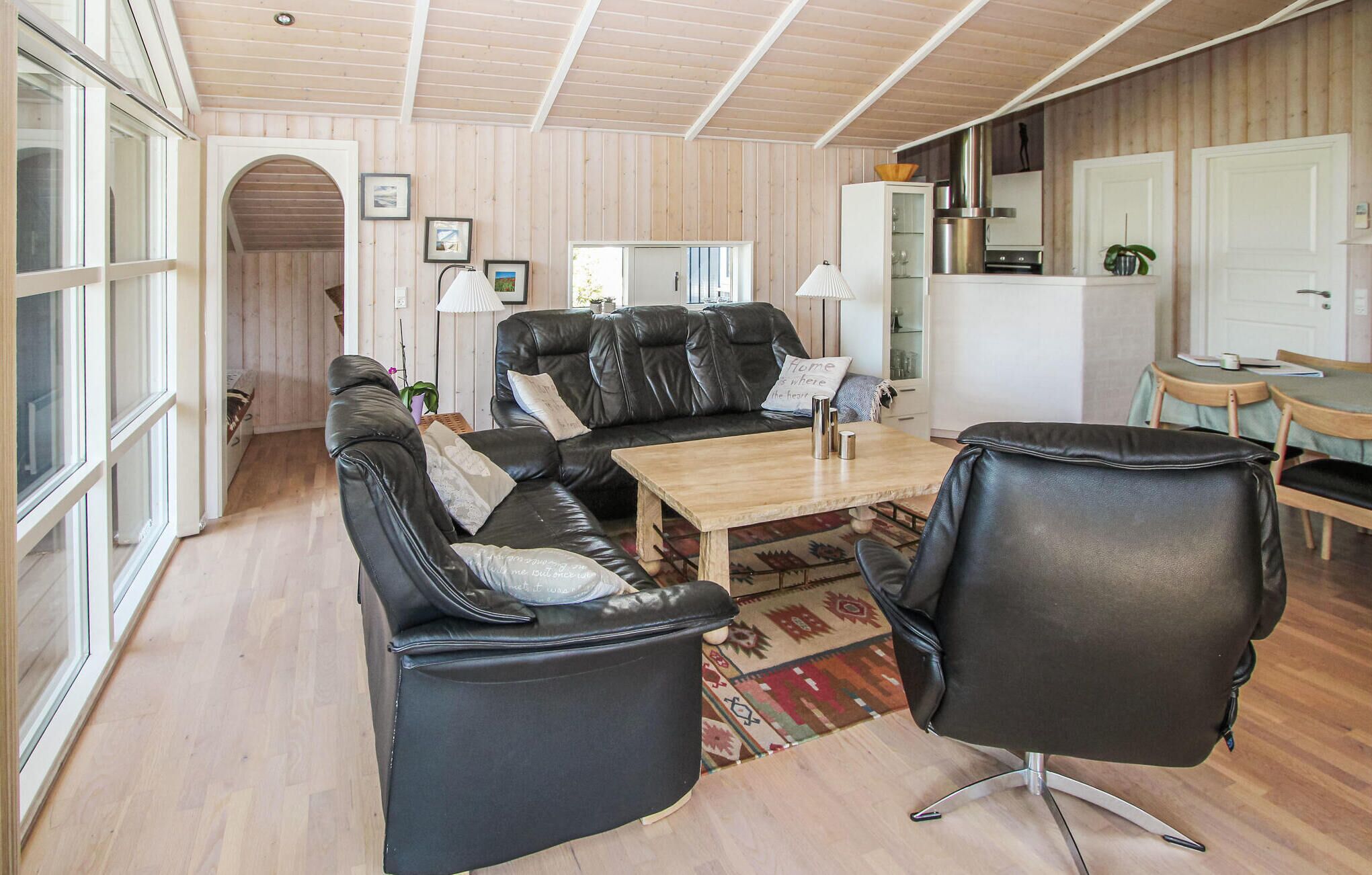 A cozy living room with a leather sofa, a wooden coffee table, and a patterned rug.