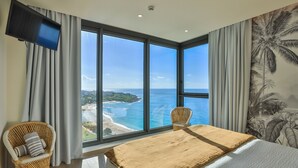 Un dormitorio con una ventana grande, una cama, una silla y un televisor.