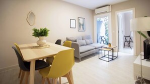 Uma sala de estar moderna com um sofá, uma mesa de jantar com cadeiras, uma mesinha de centro e um rack para TV.