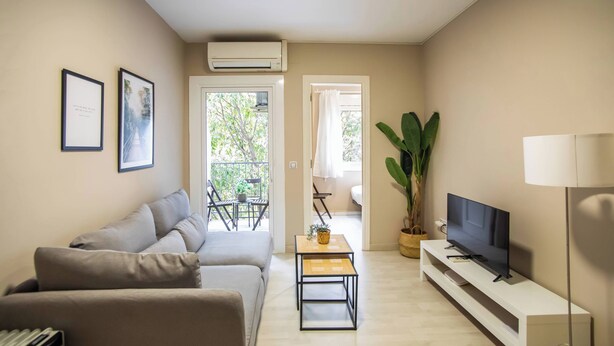 Sala de estar com sofá, televisão e planta em vaso.
