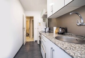 A modern kitchen with white cabinets, a granite countertop, a stainless steel sink, and a coffee maker. - 12TOGO1035 - Spacious Apartment near Camp Nou! (Barcelona)