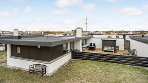 A modern residential building with a flat roof, a patio area with outdoor furniture, and a view of the surrounding landscape. - Awesome home in Pandrup with WiFi (Pandrup)