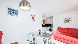 A compact living space with a dining area, a red sofa, and a kitchen in the background. - Stunning apartment in Saint Cyprien Plage (Saint Cyprien Plage)
