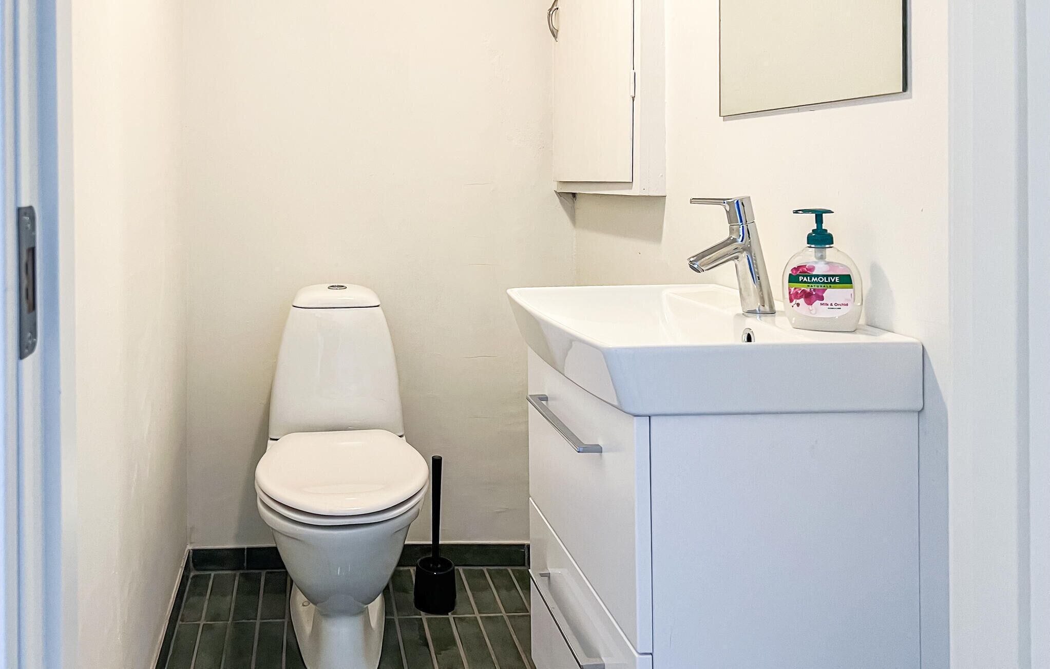 Ein kleines Badezimmer mit Toilette, Waschbecken und einer Seifenspender.