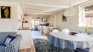 A cozy room with a checkered sofa, a dining table with a patterned tablecloth, and a kitchen in the background. - Awesome home in Samsø with WiFi (Samsø)