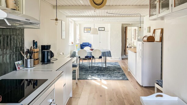 A modern kitchen with a central island, a dining area with a blue chair, and a white refrigerator. - Awesome home in Samsø with WiFi (Samsø)
