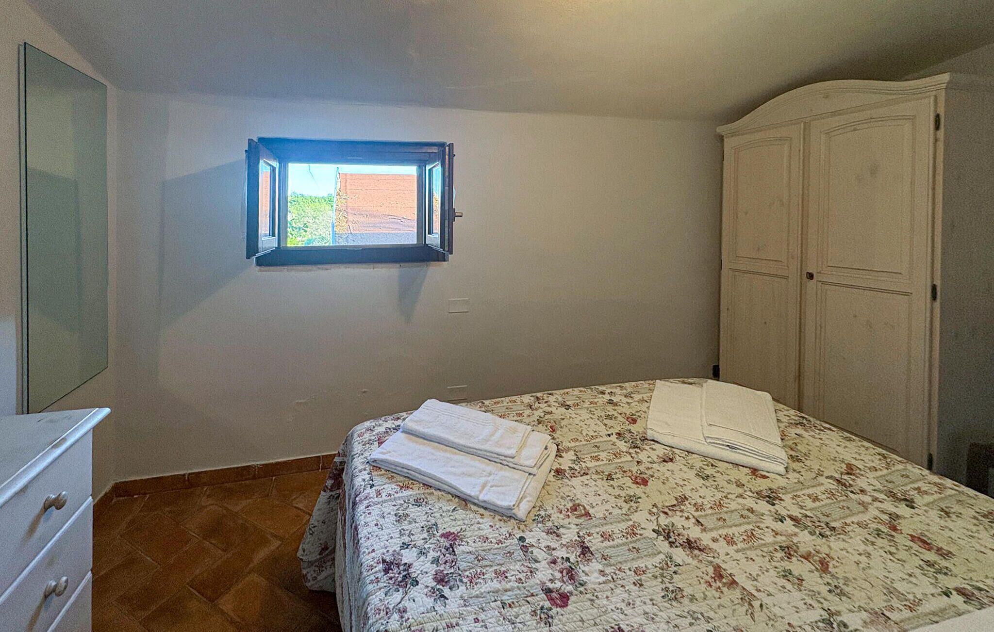 A bedroom with a bed, a window, a wardrobe, and a dresser.