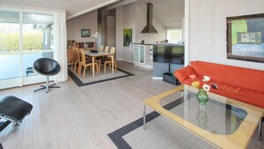 A modern living room with a glass coffee table, a red sofa, and a dining area with wooden chairs. - Awesome home in Samsø with kitchen (Samsø)