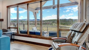 A room with a large window offering a view of a mountainous landscape. There is a massage chair and a blue sofa.