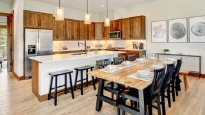 A modern kitchen with wooden cabinets, a central island, and pendant lighting.