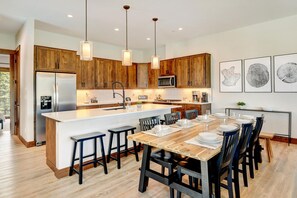 A modern kitchen with wooden cabinets, a central island, and pendant lighting.