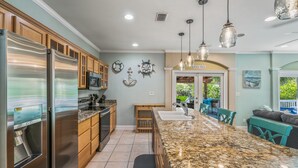 A modern kitchen with granite countertops, stainless steel appliances, wooden cabinets, and pendant lighting. - Private Pool! Golf Cart! Bikes! 143 Beth Lane! (Santa Rosa Beach)