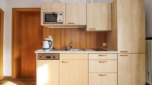 Een compacte keuken met houten kastjes, een Bosch vaatwasser, een magnetron en een koffiezetapparaat.