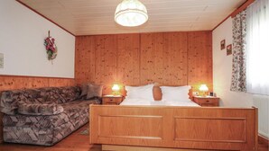 Een slaapkamer met een houten bed, een gestreept bankje en twee bedlampjes.