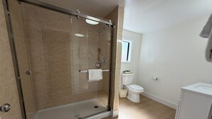 A bathroom with a glass-enclosed shower, a toilet, and a sink.