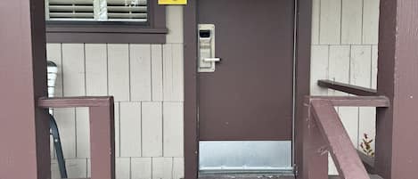 Una puerta marrón con un letrero que dice 'SPYGLASS', una ventana con persianas y un banco en el exterior.