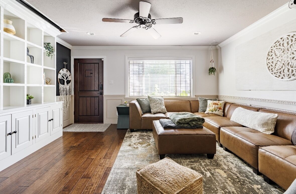 A living room with a brown leather sofa, a white cabinet, and a ceiling fan.
