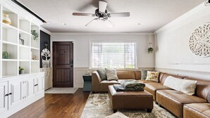 Ein Wohnzimmer mit braunem Ledersofa, einem weißen Schrank und einem Deckenventilator.