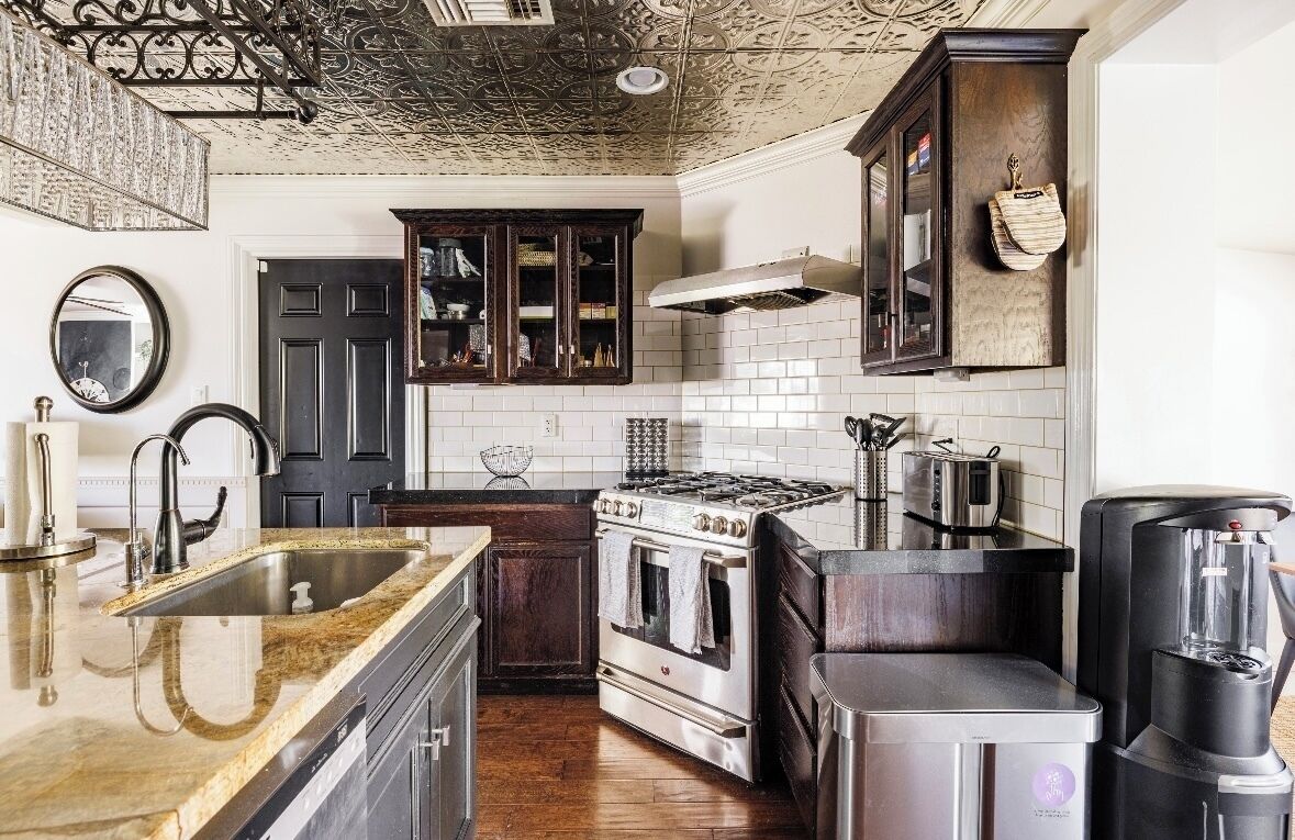 A kitchen with a granite countertop, stainless steel appliances, and dark wooden cabinets.