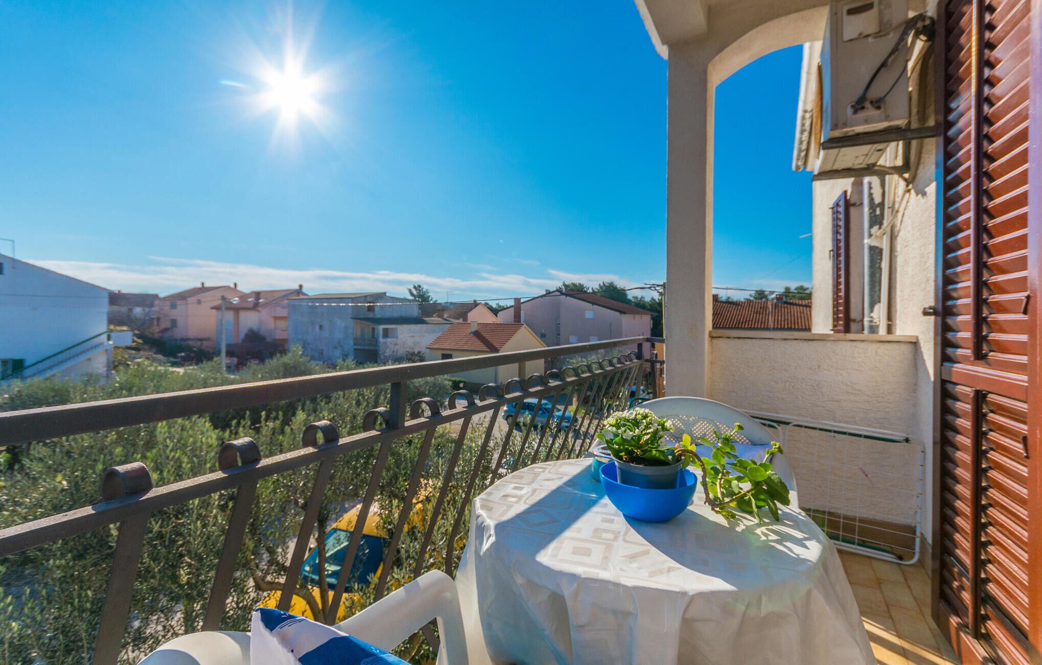 Ein Balkon mit Tisch, Blumentopf und Blick auf die Nachbargebäude.