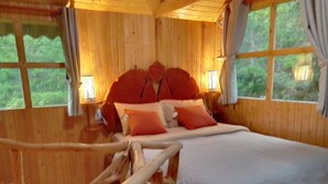 A wooden cabin bedroom with a bed, pillows, and a nightstand.