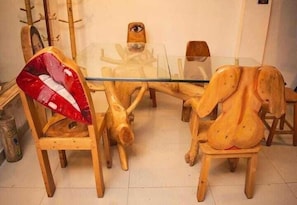 Un comedor con una mesa de vidrio rodeada de sillas de madera y una silla roja y blanca distintiva.