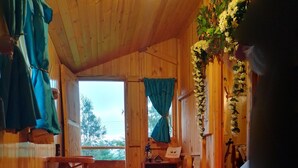 A wooden interior with a rustic aesthetic, featuring a wooden table, a bench, and a wooden stool.