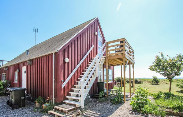 A red barn with a wooden staircase leading to a porch.
