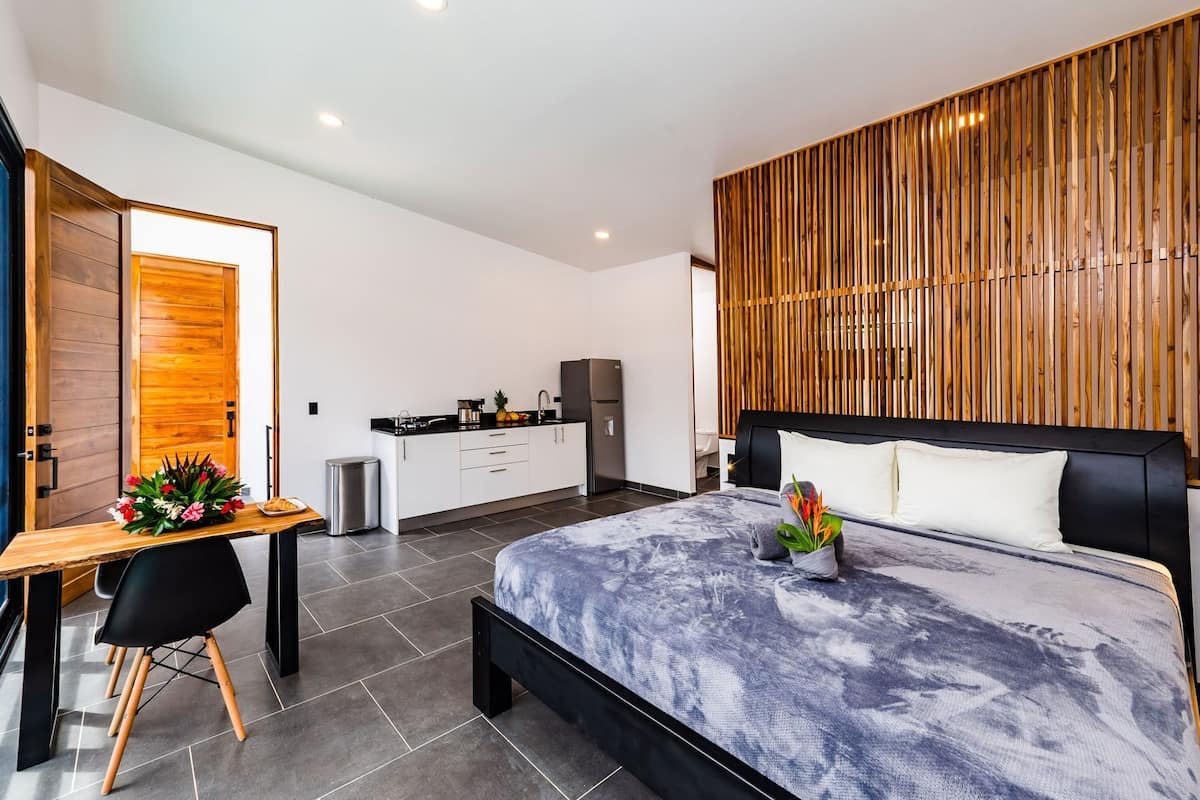 Un dormitorio moderno con cama, escritorio y kitchenette.