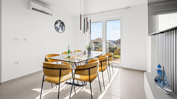 Un coin repas avec une table en verre, six chaises, une horloge représentant une carte du monde et une vue sur l’extérieur.