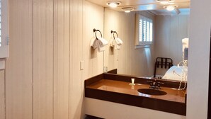 Une salle de bain avec un meuble-lavabo en bois, un évier, un miroir et deux serviettes suspendues à des crochets.