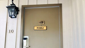 Une porte de couleur beige, dotée d’une poignée en métal et d’une plaque au-dessus indiquant « PEBBLE 112 ».
