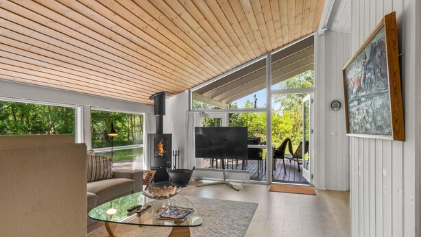 Un salón moderno con una mesa de centro de cristal, un sofá, una chimenea y un cuadro en la pared.