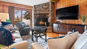 Una sala de estar acogedora con chimenea de piedra, televisor de pantalla plana y paredes de madera.