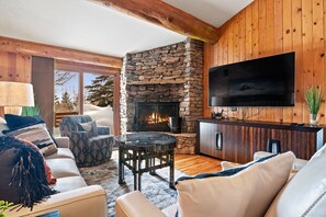 Un salon chaleureux avec une cheminée en pierre, un téléviseur à écran plat et des murs en bois.